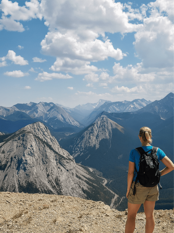 Woman hiking on Skyline Trail Alberta with panoramic mountain views under a bright summer sky.